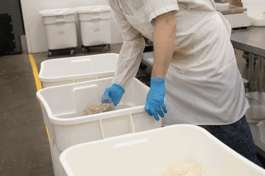 Michele's Granola bakery team measuring ingredients into bins, protein-rich foods for meal preparation.