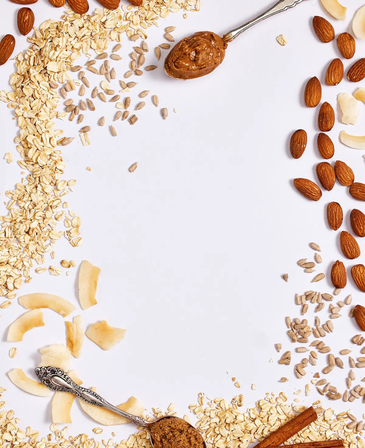 Michele's Granola nuts, seeds, and dried fruits arranged around a spoonful of peanut butter on a white background.