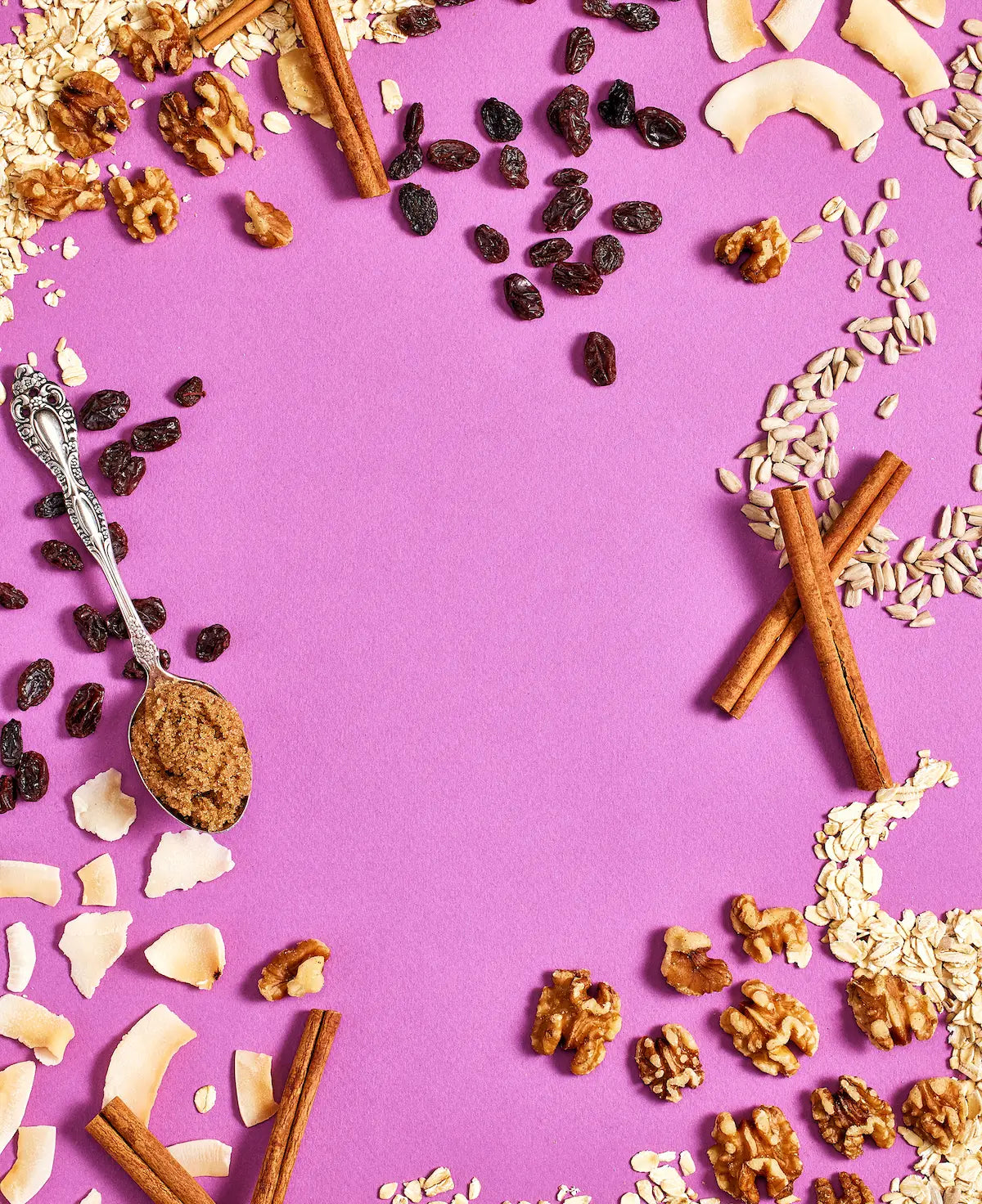 Michele's Granola spices, nuts, and dried fruits on a purple background with a spoon.