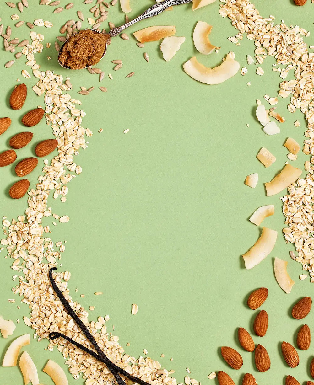 Michele's Granola spices, oats and nuts arranged on a green background
