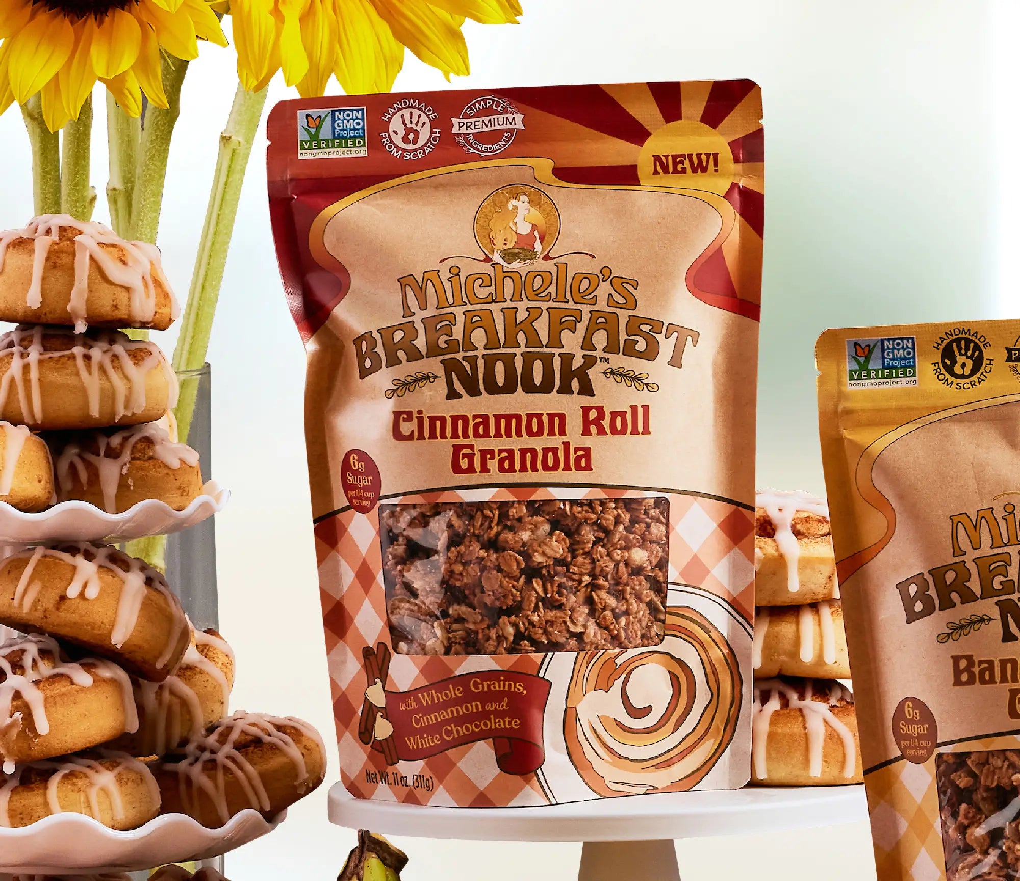 Michele's Breakfast Nook Cinnamon Roll Granola package with a stack of cinnamon roll donuts and sunflowers.