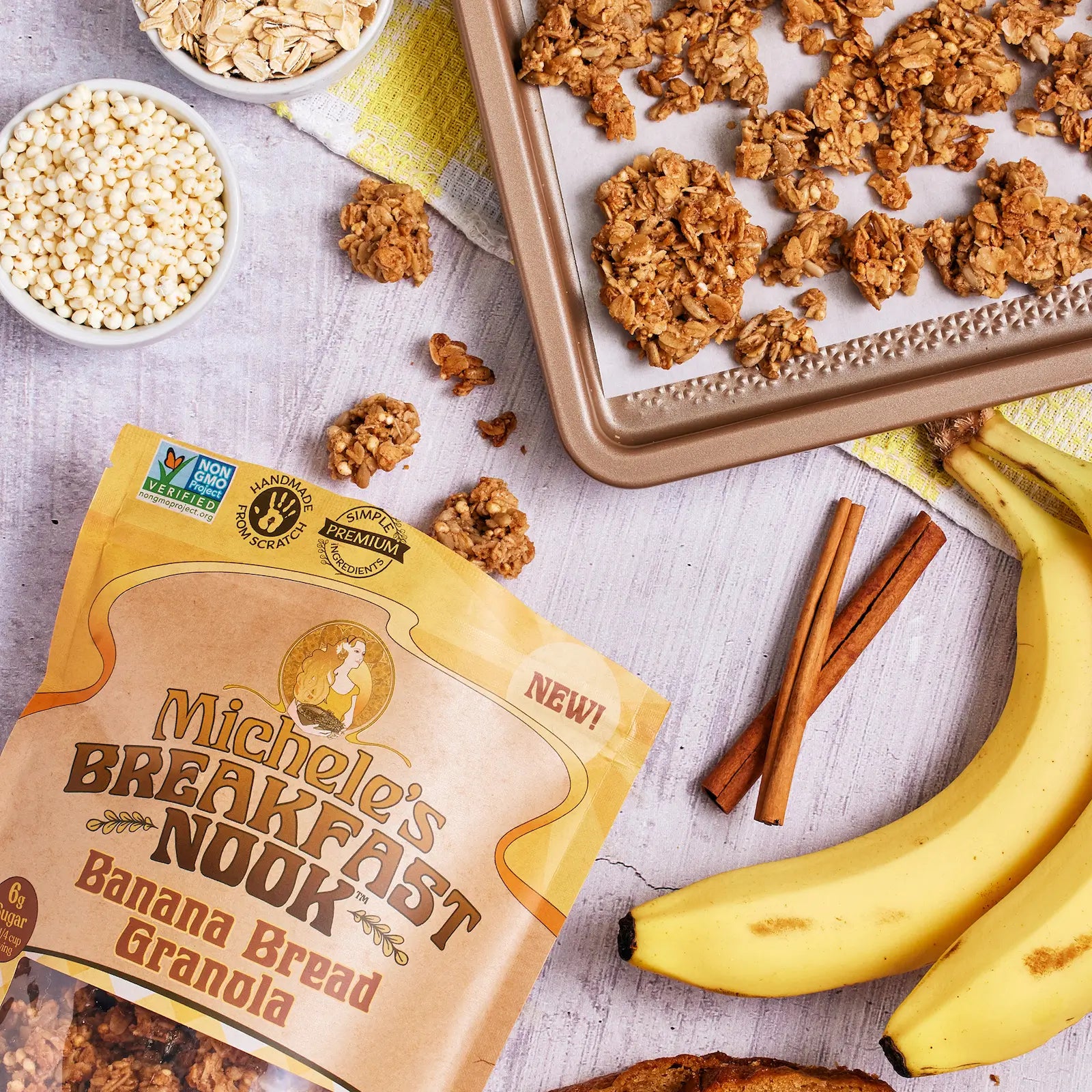 Michele's Breakfast Nook Banana Bread Granola package with granola, bananas, and cinnamon sticks on a light surface.